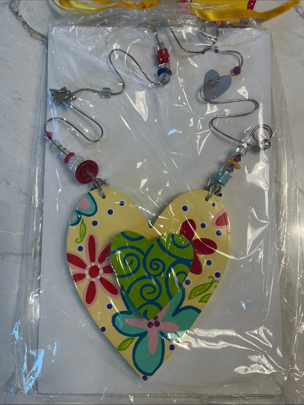 Hannabellโs Yellow Heart Wall Accessory with Multicolor Floral Accents